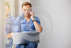 Young creative man working with computer while talking on phone