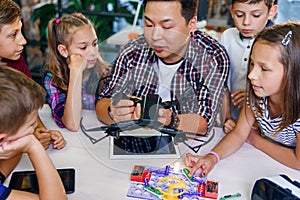 Young creative teacher explains for students the principle of quadcopter work.