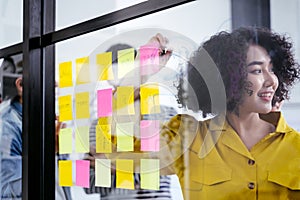 Young creative team use post it notes to share idea sticky note on glass wall.
