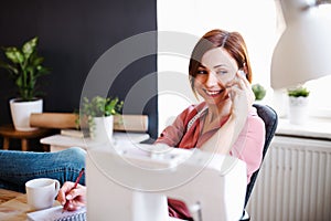 Young creative woman in a studio, using smartphone. A startup of tailoring business.