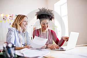 Young creative women with laptop in a studio, startup business.