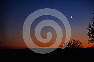 Young crescent moon on a clear sky at the end of the day in the summer