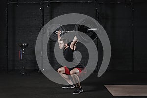 Young cross fit athlete doing squats with barbell over head. Man practicing functional training.Powerlifting workout exercises