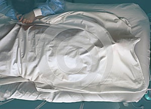 Young crying woman next to the deathbed of covered with bedsheet dead man photo