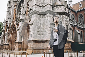 The young and curious traveller is standing on the corner of the street near the big church building