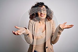 Young curly arab business woman wearing elegant jacket and glasses over white background clueless and confused expression with