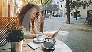 Young curly brunette in cafe with digital pad