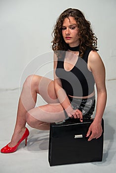 Young curly brunette woman ready to go to the office with her black bag.