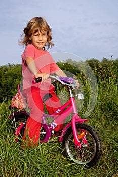 Young curly girl biker rests in the field