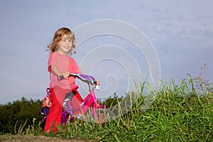 Young curly girl biker rests in the field