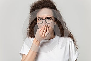 Young curly girl clenching nose, feeling unpleasant smell.