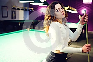Young curly girl posed near billiard table