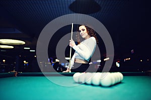 Young curly girl posed near billiard table