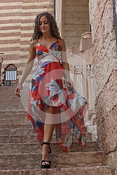 Young curly girl with red colored sleeveless summer dress with flowers.