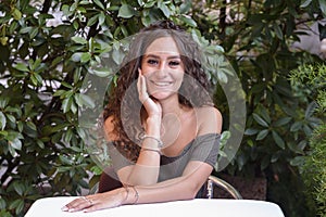 Young curly girl sitting in the restaurant waiting to have lunch.