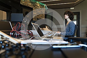 Young curly hair caucasian woman working in a music studio