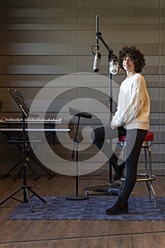 A young curly hair singer woman recording a song in a real studio. Vertical photo