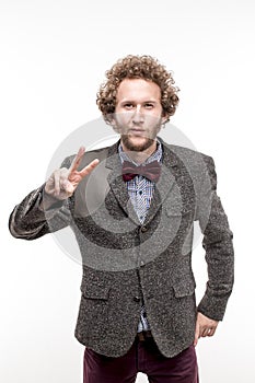 Young curly-haired businessman wearing brown suit gesturing with a V-sign on a white background. World. isolate