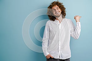 Young curly man with ginger hair laughing and pointing finger aside