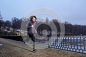 Young curly man jogging in the park spring afternoon