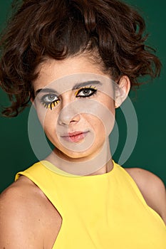 young curly woman with creative make-up in yellow dress