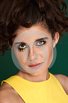 young curly woman with creative make-up in yellow dress