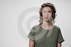 Young curly woman with puzzled raises eyebrows negative facial expression