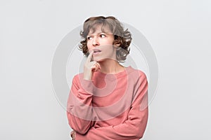 Young curly woman thinking and pondering over something