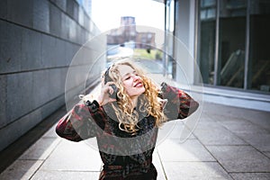 Young curly woman using her phone and relax in the city