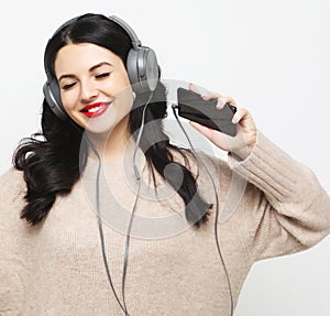 Young curvy brunette woman in headphones listening to music