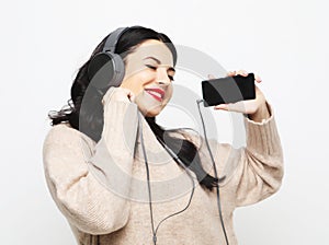 Young curvy brunette woman in headphones listening to music