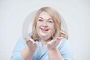 Young curvy fat woman sends an air kiss to the camera. White background.