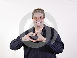 Young curvy man posing in a white background isolated smiling and showing a heart shape with hands