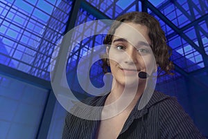young customer support service representative woman operator with headset on blue glass building window