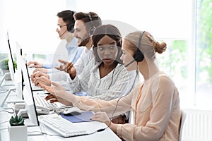 Young customer support workers solving clients problem together at call centre office