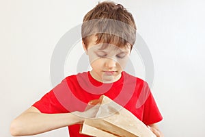 Young cut boy take out something from a paper package on white background