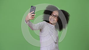 Young cute African girl with Afro hair using phone