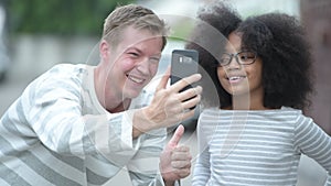 Young cute African girl with Afro hair and young Scandinavian man together in the streets outdoors