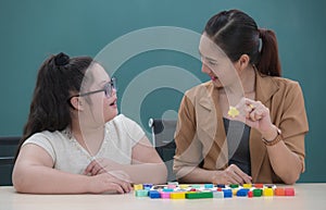 Young and cute Asian teacher teaching small down syndrome gils to play the toys in classroom