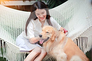 Young and cute asian women lying in a hammock and playing with dog during holiday