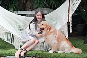 Young and cute asian women lying in a hammock and playing with dog during holiday