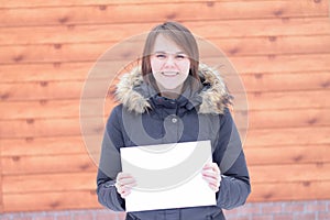 Young cute beautiful girl in a jacket in winter clothes on the background of a boardwalk