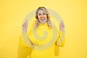 Young cute beautiful happy smiling woman wearing yellow sweater standing over yellow isolated background, pointing with hands to photo