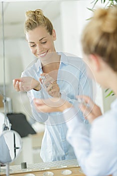 Young cute beautiful woman putting on perfume