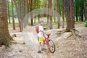 Young cute boy in helmet rides a bicycle in the park. Boy goes on the road. Sport