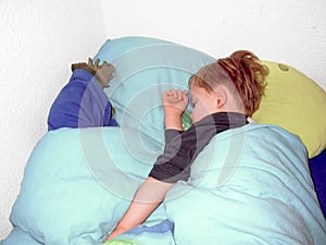 Young boy sleeping with his snuggle bun in bed, a dinosaur