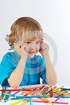 Young cute boy at the table with color pencils