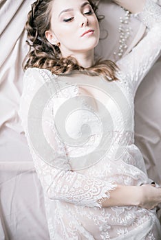 Young cute bride with beautiful hair in the morning at home in white negligee