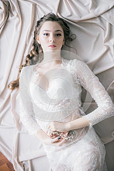 Young cute bride with beautiful hair in the morning at home in white negligee