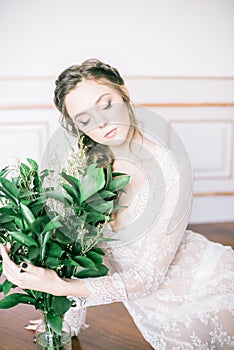 Young cute bride with beautiful hair in the morning at home in white negligee